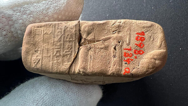 Sealed envelope A close-up of a sealed envelope with visible cuneiform script and two figures. The right one is leading the left one to the right.