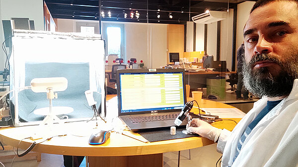 A selfie of the author during his work. On the table you see a laptop with an opened database, a seal and a USB microscope to take detailed pictures.